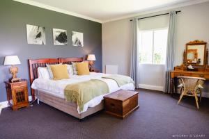 a bedroom with a bed and a desk and a window at Old Rearsby in Mooirivier