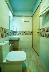 ein Bad mit einem WC, einem Waschbecken und einer Tür in der Unterkunft UMBER 6BHK VILLA ALIBAUG in Alibag