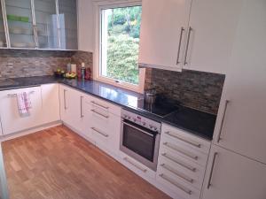 uma cozinha com armários brancos e uma janela em Toppleilighet i Fana em Bergen