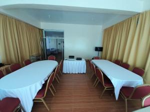 Zimmer mit 2 Tischen, Stühlen und Vorhängen in der Unterkunft Maison De Gloria in Locsin