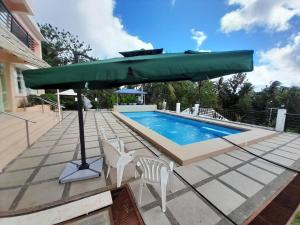 um grande guarda-chuva verde sentado ao lado de uma piscina em Maison De Gloria em Locsin