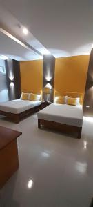 two beds in a room with yellow walls at Maison De Gloria in Daraga
