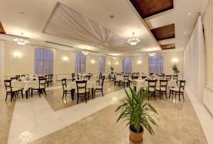 um salão de banquetes com mesas, cadeiras e janelas em Allegria Hotel em Alba Iulia