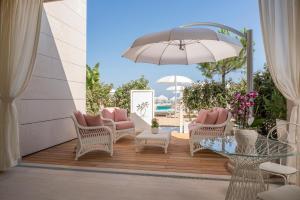 un patio con sillas, una mesa y una sombrilla en Riviera Resort Hotel, en Lignano Sabbiadoro
