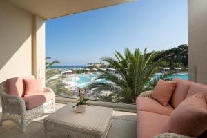 uma varanda com cadeiras cor-de-rosa e vista para a praia em Riviera Resort Hotel em Lignano Sabbiadoro