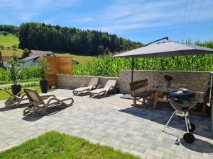 a patio with a grill and chairs and an umbrella at G5 - Das Chalet am Waldrand in Sankt Stefan im Rosental
