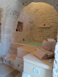 a stone bathroom with a tub and a sink at Trullo del Sol in Ceglie Messapica