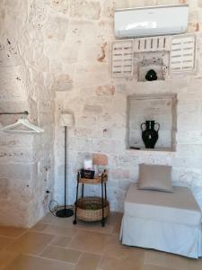 a room with a stone wall with a bed and a lamp at Trullo del Sol in Ceglie Messapica