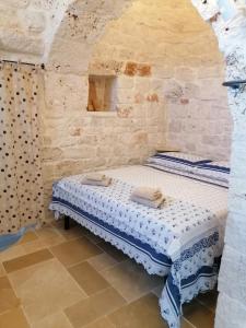 um pequeno quarto com uma cama numa parede de pedra em Trullo del Sol em Ceglie Messapica