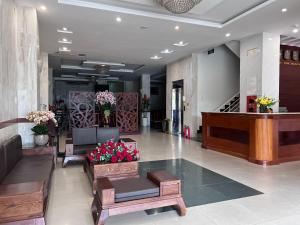 a lobby with couches and a piano and flowers at AMANDA HOTEL ĐÀ NẴNG in Da Nang
