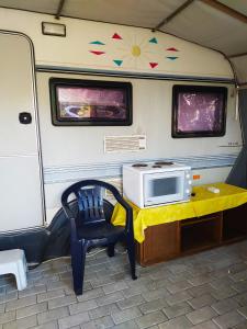 a microwave on a table with a chair in a trailer at camping hydraswave bungalow caravan in Thermisía