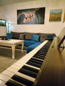a living room with a blue couch and a piano at ArtePovera Apartment Tuzla in Tuzla