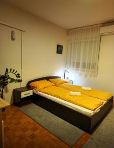 ein Schlafzimmer mit einem großen Bett mit gelber Bettwäsche in der Unterkunft ArtePovera Apartment Tuzla in Tuzla
