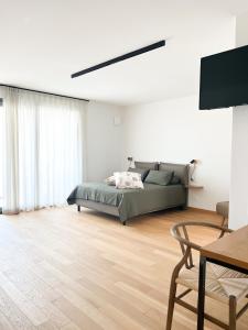 a white bedroom with a bed and a table at Glass House - Smart Rooms & Parking in Lecce