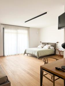 a white bedroom with a bed and a table at Glass House - Smart Rooms & Parking in Lecce