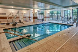 a pool in a hotel with chairs and tables at Courtyard Newport News Airport in Newport News