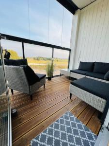 een afgeschermde veranda met stoelen en een bank bij Koselig studioleilighet in Jessheim