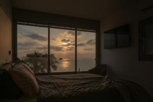 Un dormitorio con una ventana con vista al mar. en Beachfront Elegance - Luxe Abode!, en Netanya