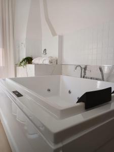 uma casa de banho branca com uma banheira e um lavatório em Geometric Hermes Bianca em Palo del Colle