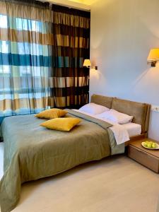 Un dormitorio con una cama con almohadas amarillas y una ventana en Апартаменты Ясная Поляна en Odesa