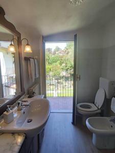 uma casa de banho com 2 lavatórios e um WC e uma porta em Mo&Ma - Panorama e relax em Maccagno Inferiore