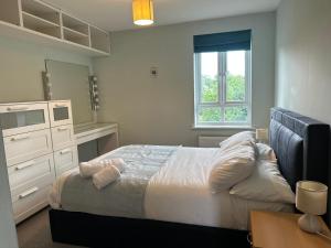 a bedroom with a bed and a dresser and a window at Cosy 2 Bedrooms 2 Bathrooms in Basingstoke