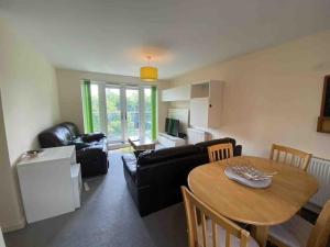 uma sala de estar com uma mesa e um sofá em Cosy 2 Bedrooms 2 Bathrooms em Basingstoke