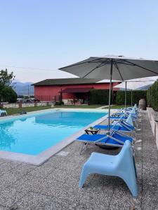 a row of blue chairs and an umbrella next to a swimming pool at B&B Colle Cucchiara in Cassino