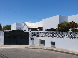 ein weißes Gebäude mit einem schwarzen Tor auf einer Straße in der Unterkunft Casa El Eco del Volcán 1 in Teguise