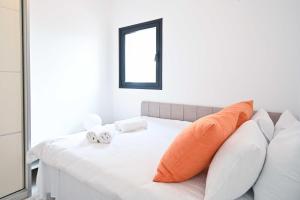 a white bed with orange pillows and a mirror at NOGA vibes 2BR in JAFFA by Holyguest in Tel Aviv