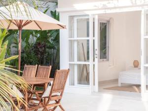 a wooden table with two chairs and an umbrella at Casa Majorca at Ulu in Uluwatu