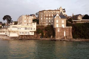 un grupo de edificios en una colina junto a un cuerpo de agua en Le Petit Saint Cast - Cocon vue Mer, en Saint-Cast-le-Guildo