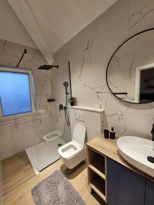 bagno con servizi igienici, lavandino e specchio di Villa LUX Apartments a Rogoznica (Rogosnizza)