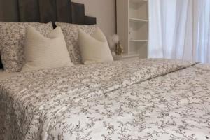 a bed with a white comforter and white pillows at Les Grenats in Conflans-Sainte-Honorine
