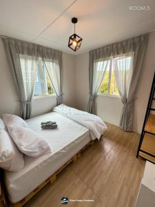 a bedroom with a large bed with two windows at Qloud Cottage in Ranau