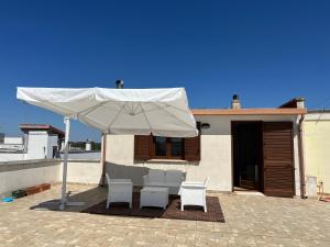 un patio con un ombrellone bianco e due sedie di FH HOLIDAYS SALENTO a Sternatia