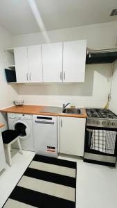 a kitchen with white cabinets and a sink and a stove at Warszawa Wola Pokoje in Warsaw