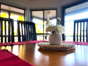 un jarrón lleno de flores blancas sentado en una mesa en Ocean View 3 bedroom entire house central of Caloundra en Caloundra West