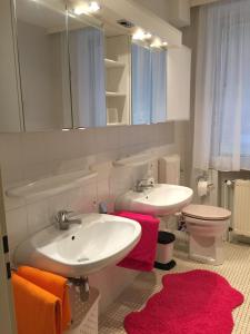 ein Badezimmer mit zwei Waschbecken, einem WC und einem Spiegel in der Unterkunft Ferienwohnung Landhaus Hohenstein, Schwimmteich, ruhige Lage in Hessisch Oldendorf