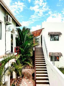 eine Treppe, die zu einem weißen Gebäude mit Palmen führt in der Unterkunft CeZeRe THE PALM HOTEL in Paje