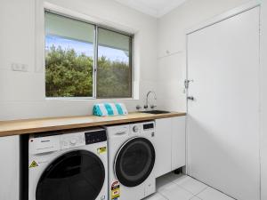lavadero con lavadora y secadora y ventana en Picture-Perfect Mornington Getaway, en Mornington