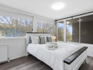 a bedroom with a large white bed and large windows at Picture-Perfect Mornington Getaway in Mornington