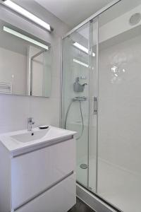 La salle de bains blanche est pourvue d'un lavabo et d'une douche. dans l'établissement Cosy Deauville, à Deauville