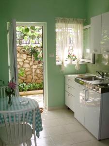 a kitchen with green walls and a table and a sink at Apartments Mara in Mali Lošinj
