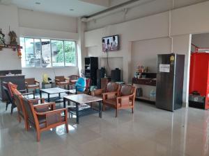 a living room with chairs and tables and a refrigerator at โรงแรม นิววันชัย โฮเต็ล in Ban Sao Thong