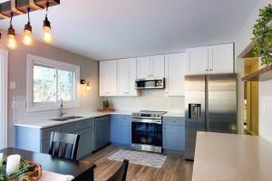 une cuisine avec des placards blancs et une table ainsi qu'une cuisine avec des appareils bleus dans l'établissement Book Entire House, 3 Bedrooms in White Bear Lake, à Saint Paul