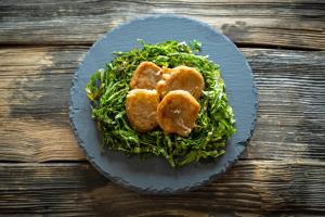 a plate of food with greens on a wooden table at Albergo San Michele in Tirano