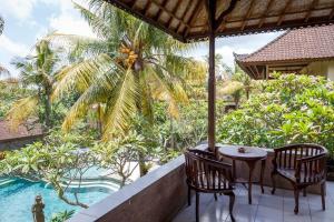 a patio with a table and chairs and a pool at White House in Ubud