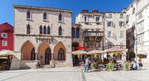 a group of buildings with tables and chairs in a street at Apartment Stone in Split