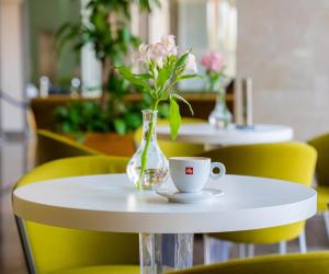 una mesa blanca con un jarrón de flores y una taza en Marina Hotel, en Kuwait